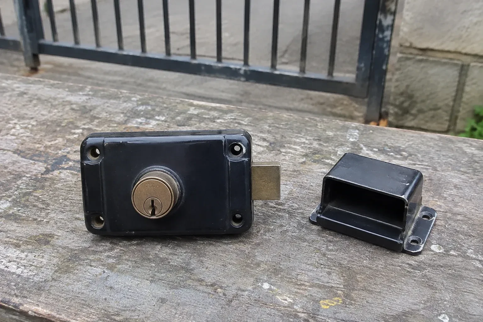 Detached rim gate lock and separate box keeper on an outdoor workbench. — Gate & Building Entry Locks, Niagara Falls